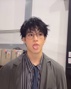 a young man wearing glasses and a tie making a funny face at the camera with his tongue out