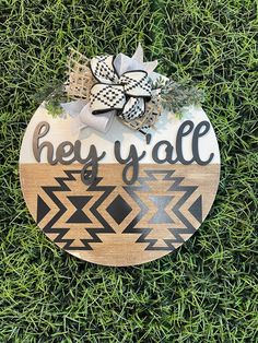 a wooden sign that says hey y'all on it in the grass with a bow