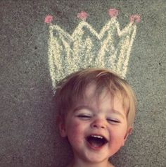 a little boy laying on the ground with a crown drawn on it's head