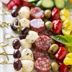 several skewered meats and vegetables on a white plate