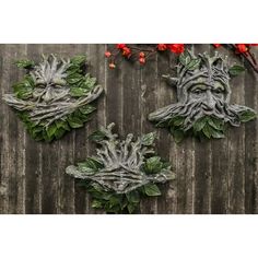 three green man faces with leaves and red flowers on a wooden background, set of 3