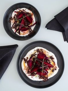 two black plates topped with food on top of a white table