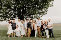 a large group of people standing next to each other in front of a big tree