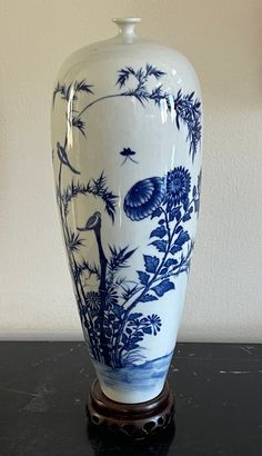 a blue and white vase sitting on top of a black table next to a wall