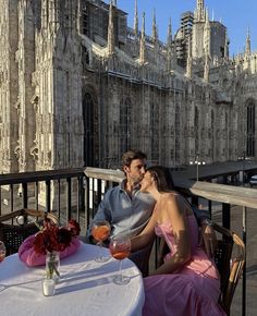 a man and woman sitting at a table in front of a cathedral