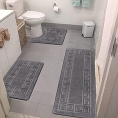 three bathroom rugs are placed on the floor in front of a toilet and sink