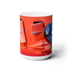 an orange and white coffee mug with a red car's hood on the front