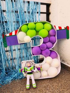 the letter e is decorated with balloons and a toy astronaut standing next to it in front of a balloon wall