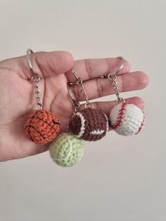 three small crocheted balls are being held by a person's left hand