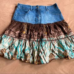 a skirt made out of jeans and fabric on top of a bed with a brown blanket