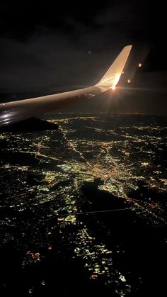 an airplane wing flying over the city lights at night