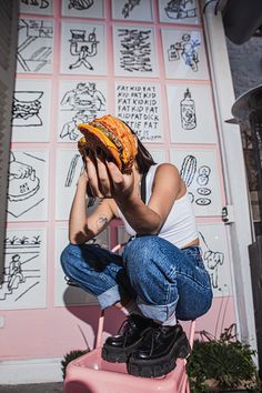 a woman sitting on top of a pink suitcase holding a piece of food up to her face