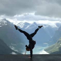 a person doing a handstand in front of mountains