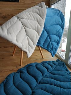 two blue and white mattresses sitting next to each other in front of a window