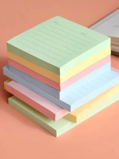 five sticky notes stacked on top of each other next to a pen and paper pad