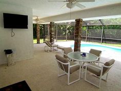 a patio with chairs and a table next to a pool