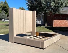 a bed frame made out of concrete sitting in the middle of a driveway next to a house