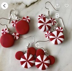 four red and white candy cane earrings on a marble countertop with the letters abc