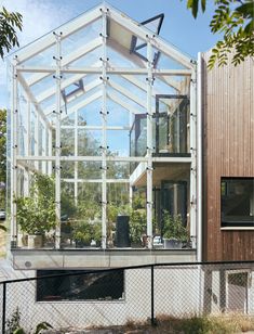 the house is made up of glass and wood, with plants growing in it's windows