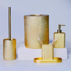 gold bathroom accessories including soap dispenser, toothbrush holder and toilet brush