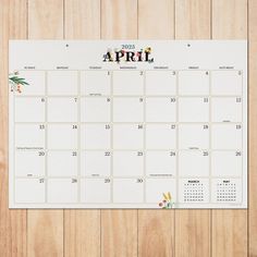 a calendar on a wooden surface with the word apri written in red and yellow