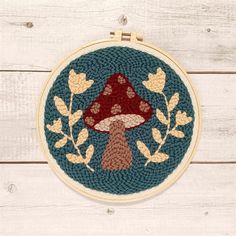 a cross stitch pattern with a mushroom in the center and leaves around it on a wooden surface