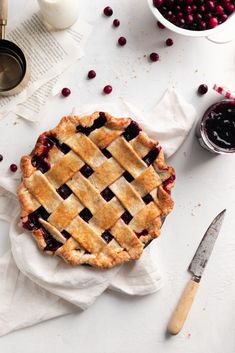 a pie sitting on top of a white table next to some cranberry sauce