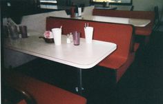 two tables with red chairs and white table cloths in a fast food restaurant setting