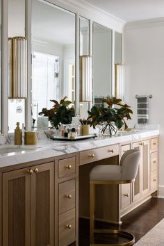 an elegant bathroom with marble counter tops and gold accents, along with large mirrors on the wall