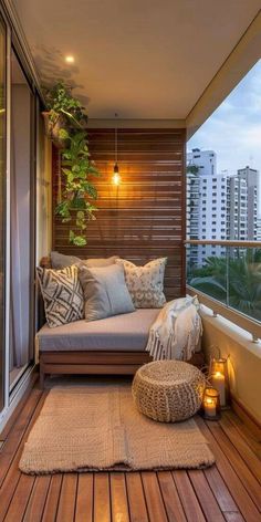 a balcony with wooden flooring and lots of pillows on the couches, along with candles