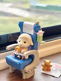 a teddy bear sitting in a blue chair next to a window sill with a stuffed animal on it