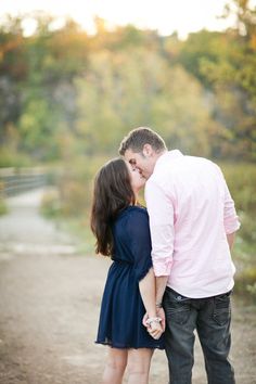 an engaged couple kissing on a dirt road