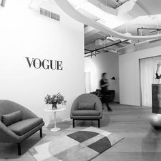 black and white photograph of an office with two chairs in front of a wall that says voque