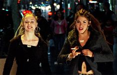 two women are walking down the street at night with their hands in each others pockets