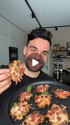 a man is holding up some pizzas on a pan