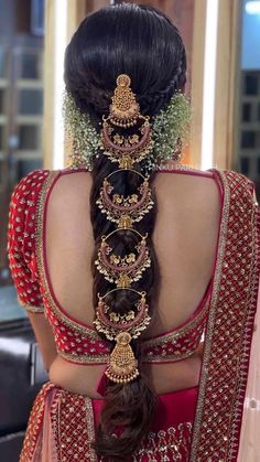 a woman with long hair wearing a red and gold bridal gown, braided into a