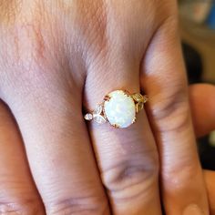 a woman's hand with a ring on it that has a white opal in the middle