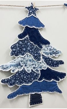 a blue and white christmas tree hanging from a string on a wall with some fabric