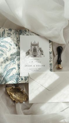 the wedding stationery is laid out on top of white sheets and paper with a gold stamp