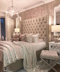 a bedroom with a large bed, mirrored nightstands and chandelier above it