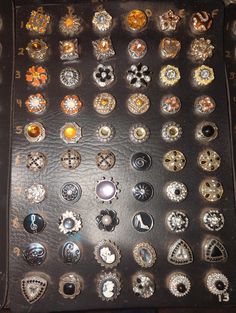 an assortment of brooches are displayed on a black leather surface with gold and silver accents