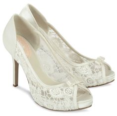 a pair of white high heels with lace on the top and heel, in front of a