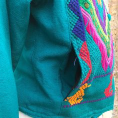 Inspired by the beauty of Mexico this vivid, coloring bursting embroidery jacket is a real eye-catcher. The fabric was made from scratch using a loom, thread by thread. 100% cotton. Partially Lined with Fleece so it’s a very warm piece, has one interior secret pocket and 2 pockets at the front also lined with fleece. MADE IN MEXICO By: Mexican Artisans For: Women Size: Medium (view size chart) Color: teal | multi Details: 100% cotton Embroidery Toggle button closure Shoulder pads 2 front pockets Artisan Long Sleeve Cotton Outerwear, Traditional Green Top For Fall, Traditional Green Tops For Fall, Green Traditional Top For Fall, Cotton Outerwear With Geometric Embroidery For Fall, Bohemian Cotton Outerwear With Woven Motifs, Traditional Green Cotton Outerwear, Folk Style Cotton Outerwear With Geometric Embroidery, Embroidered Green Cotton Outerwear