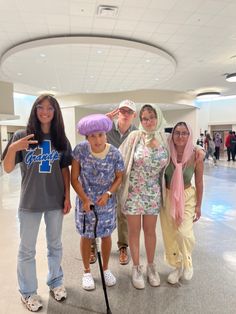 a group of people standing next to each other in an airport lobby, posing for the camera