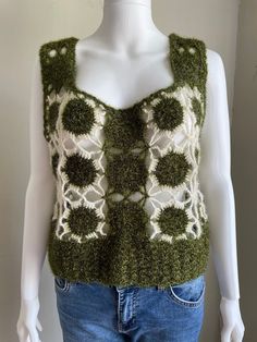 a white mannequin wearing a green and white knitted top with flowers on it