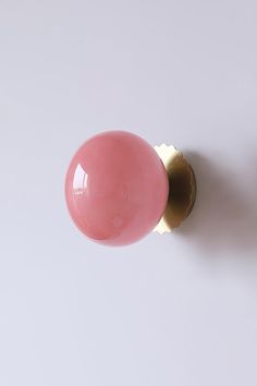 a pink door knob on a white wall