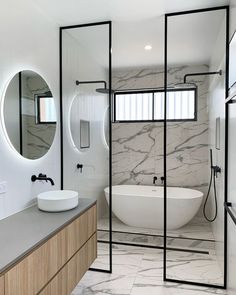 a bathroom with marble walls and flooring, two round mirrors above the bathtub