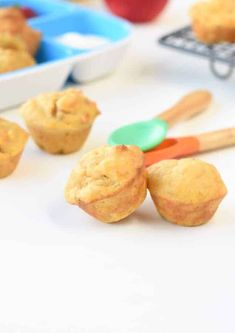 some muffins are sitting on a table with spoons and bowls in the background