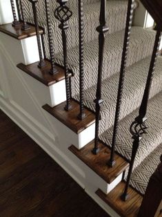 a set of stairs with wooden handrails and black iron balustiers on them