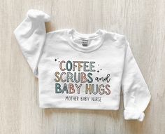 a white sweatshirt with tiny humans and tall coffees written on the front in multicolored letters